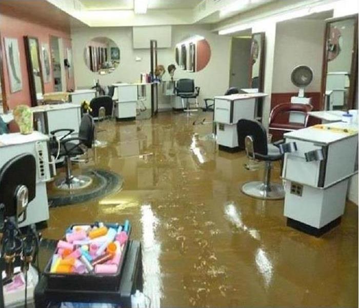 salon with brown water covering the floor, white roll desks and black chairs
