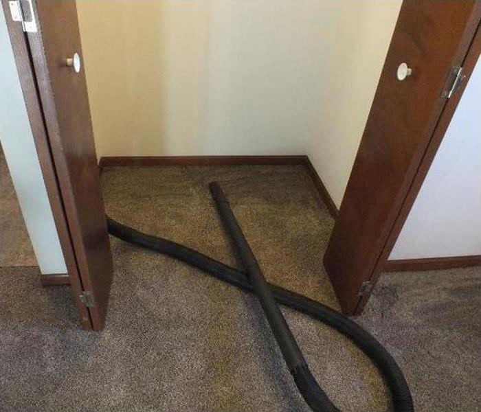 Concrete flooring with doors and a black hose on the floor