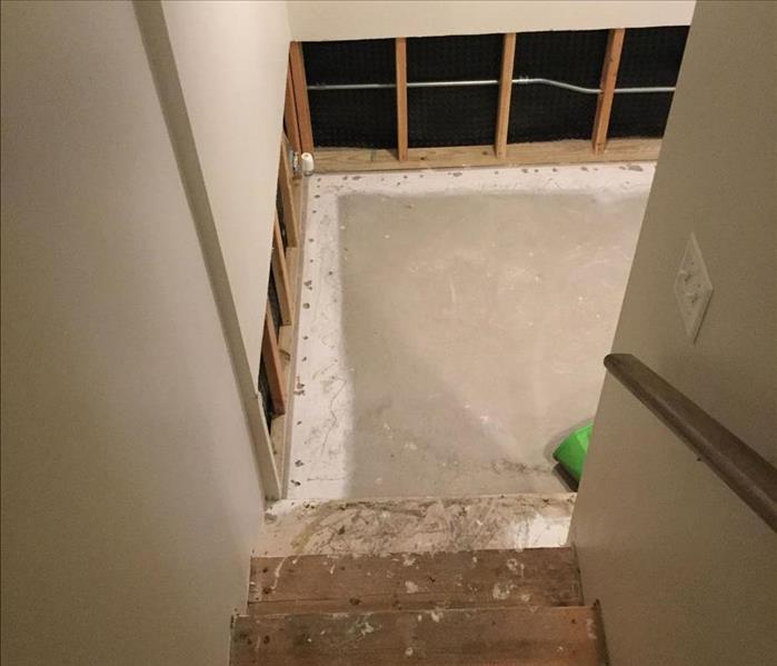 Damaged stairs with removed flooring and drywall at the landing. SERVPRO equipment is visible near the bottom stair