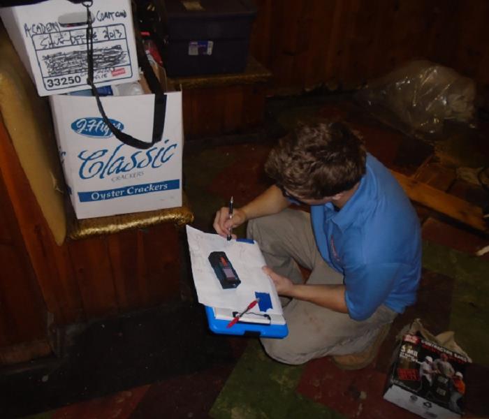 A man kneeling down in a room with a blue shirt on