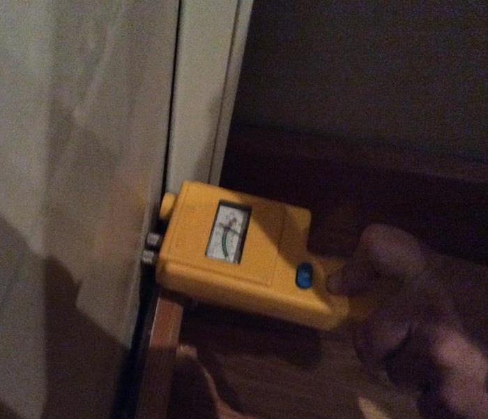 yellow moisture meter pressed into a wet wall