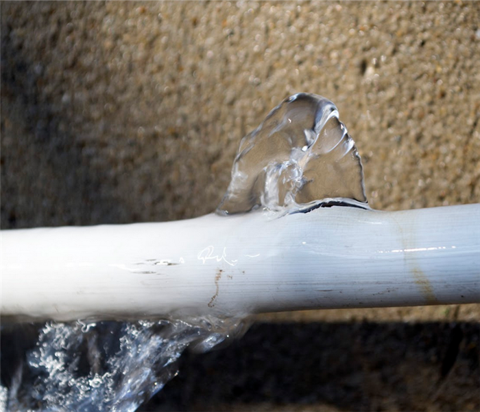 a broken white pipe that is leaking water
