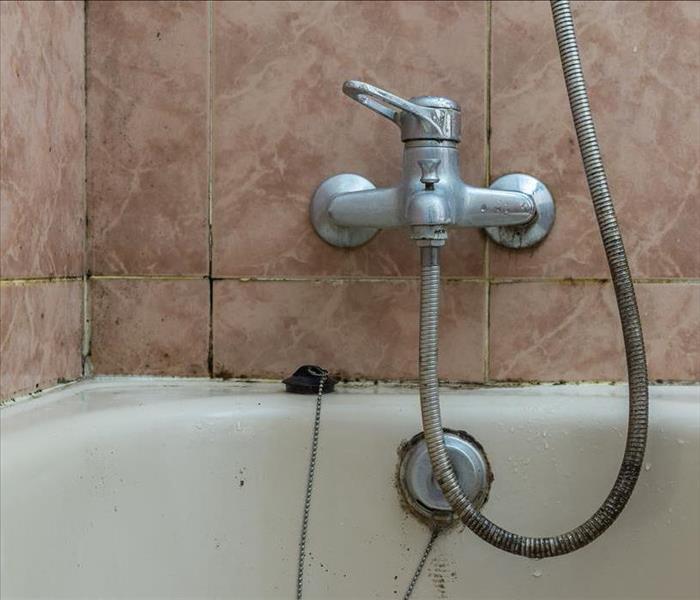 Off pink tile and water faucet to a bathtub 